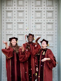 a group of people in graduation robes are throwing confetti