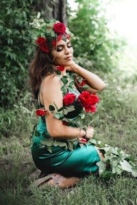 a woman in a green dress with roses on her head